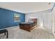 Cozy bedroom with carpet, a wood bed frame, natural light, and blue accent wall at 7616 Derrek Pl, Indianapolis, IN 46219