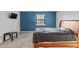 Bedroom with blue accent wall, wood-frame bed, window, and television on the wall at 7616 Derrek Pl, Indianapolis, IN 46219
