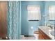 A functional bathroom with a shower curtain, wood cabinet vanity, and a neutral-colored tile floor at 8306 Corkwood Dr, Indianapolis, IN 46227