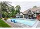 Backyard oasis featuring a sparkling pool, patio area with comfortable seating, and mature trees at 8651 Emerald Ln, Indianapolis, IN 46260