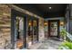 A covered porch featuring stone accents, glass doors and stylish outdoor lighting at 8651 Emerald Ln, Indianapolis, IN 46260