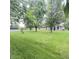 Spacious backyard featuring lush green grass, mature trees, and a charming lattice-enclosed porch at 907 Corey Ln, Plainfield, IN 46168
