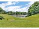 Expansive backyard lawn leading to a tranquil lake, framed by lush greenery for a serene outdoor retreat at 9231 E Poynter Dr, Morgantown, IN 46160