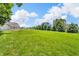 Vast backyard with a brick home and storage shed, surrounded by trees, under a bright blue sky with scattered clouds at 9231 E Poynter Dr, Morgantown, IN 46160