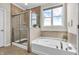 Modern bathroom featuring a glass shower, soaker tub, and bright window with blue sky view at 9231 E Poynter Dr, Morgantown, IN 46160