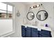 Bright bathroom with a double sink vanity with blue cabinets, round mirrors, and a window offering natural light at 9508 Oakley Dr, Indianapolis, IN 46260