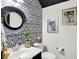 Half bath featuring patterned wallpaper, modern mirror, and framed art at 9508 Oakley Dr, Indianapolis, IN 46260