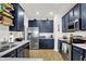 Well-lit kitchen with stainless steel appliances, navy cabinets, light countertops and wood-look flooring at 9508 Oakley Dr, Indianapolis, IN 46260
