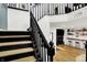 A well-lit staircase featuring a black banister, and hardwood floors at 9508 Oakley Dr, Indianapolis, IN 46260