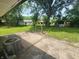 Lush backyard featuring mature trees, green grass, and a weathered concrete patio for relaxation and entertaining at 9526 Burrwood Ct, Indianapolis, IN 46235