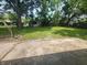 Spacious backyard with green grass and mature trees, featuring a weathered concrete patio at 9526 Burrwood Ct, Indianapolis, IN 46235