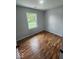 Bedroom featuring a light gray wall and warm, natural wood-toned floors complemented by a window for natural light at 9526 Burrwood Ct, Indianapolis, IN 46235