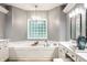 Luxurious bathroom with soaking tub, glass block window, and elegant vanity with modern fixtures at 9678 Winter Way, Zionsville, IN 46077