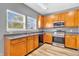 Well-lit kitchen with wooden cabinetry, stainless steel appliances, and a double sink under bright windows at 10187 Yosemite Ln, Indianapolis, IN 46234