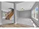Open-concept living room with neutral gray walls, plush carpeting, a staircase, and bright natural light at 10187 Yosemite Ln, Indianapolis, IN 46234