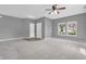 Spacious living room with gray carpet and walls, a ceiling fan, and two entry doors at 10187 Yosemite Ln, Indianapolis, IN 46234