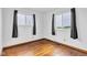 An empty bedroom with hardwood floors and two windows dressed with black curtains at 10965 W Base Line Rd, Jamestown, IN 46147