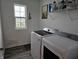 Bright laundry room features a washer and dryer with a window for natural light and storage shelves at 1439 Silver Pine Ln, Sheridan, IN 46069