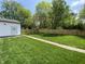 Green backyard with lush lawn, wooden fence, and walkway to a detached garage, perfect for outdoor entertaining at 1649 N Arsenal Ave, Indianapolis, IN 46218
