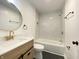 Well-lit bathroom featuring a modern vanity with gold fixtures, circular mirror, and shower-tub combo at 1649 N Arsenal Ave, Indianapolis, IN 46218