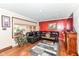 Cozy living room features a black leather sectional, vibrant red accent wall, and hardwood floors at 4080 Wander Way, Greenwood, IN 46142