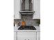 Close-up of the kitchen's cooktop with gray brick backsplash and white cabinetry at 443 Flora Pl, Carmel, IN 46290