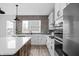 Kitchen island with white countertop, and views of the gray brick backsplash and stainless steel appliances at 443 Flora Pl, Carmel, IN 46290