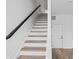 Modern staircase with white risers, wood treads, and a sleek, dark wood handrail at 443 Flora Pl, Carmel, IN 46290