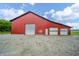Large red barn with multiple garage doors and a gravel driveway, providing ample storage and workspace at 4491 W 600 N, Anderson, IN 46011