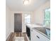 Functional laundry room with gray walls, wood-look vinyl floor, a window, and updated appliances at 4491 W 600 N, Anderson, IN 46011