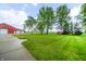 Spacious backyard with green lawn, trees, and a barn in the background, offering a serene and expansive outdoor space at 4491 W 600 N, Anderson, IN 46011