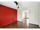Hardwood floored room with bright red accent wall and view to additional room at 4749 Rocky Knob Ln, Indianapolis, IN 46254