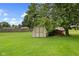 Large backyard shed situated under a mature tree with green grass at 476 Turnberry Ct, Avon, IN 46123