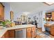 A kitchen with wood cabinets, stainless steel dishwasher, and an adjacent sitting area bathed in natural light at 476 Turnberry Ct, Avon, IN 46123