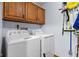 Laundry room with a side-by-side washer and dryer under oak cabinets with cleaning supplies stored nearby at 476 Turnberry Ct, Avon, IN 46123