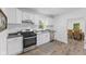Modern kitchen with stainless steel appliances, white cabinets, and hardwood floors, open to the dining area at 4836 Winthrop Ave, Indianapolis, IN 46205