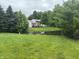 A lush backyard features a pond with lily pads, tall trees and a home in the background at 5234 Melbourne Rd, Indianapolis, IN 46228