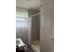 Modest bathroom featuring a shower with tile surround and a window with decorative curtains at 5312 N Kercheval Dr, Indianapolis, IN 46226