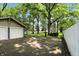Garage and basketball hoop in a spacious landscaped backyard with green grass and a white fence at 5922 Broadway St, Indianapolis, IN 46220