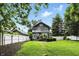 Landscaped backyard featuring a lush lawn, white fence, and a charming two-story home with a second story balcony at 5922 Broadway St, Indianapolis, IN 46220