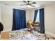 Bright bedroom featuring hardwood floors, a ceiling fan, desk, and blue curtains at 5922 Broadway St, Indianapolis, IN 46220