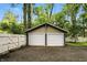 Two-car garage with white doors and a paved driveway, bordered by a white fence and foliage at 5922 Broadway St, Indianapolis, IN 46220