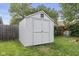 Backyard shed with double doors and a vent window on a sunny day at 5986 Regency Dr, Columbus, IN 47203