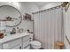 Well-decorated bathroom featuring a large round mirror, charming decor and a shower with neutral curtain at 6536 Apperson Dr, Noblesville, IN 46060
