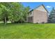 Spacious backyard with lush green grass and a partial view of a two-story brick home at 705 Ridge Gate Dr, Brownsburg, IN 46112