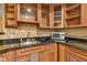 Close-up of wet bar features wood cabinets, dark granite countertop, and stainless-steel sink, perfect for entertaining at 705 Ridge Gate Dr, Brownsburg, IN 46112