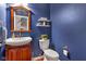 A small bathroom has blue walls, a pedestal sink, a toilet, and a wooden framed mirror at 705 Ridge Gate Dr, Brownsburg, IN 46112