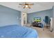 Bedroom with blue walls, neutral carpet, ceiling fan and media console. A blue covered bed is partially visible at 705 Ridge Gate Dr, Brownsburg, IN 46112