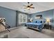Comfortable bedroom featuring blue walls, carpeted floors, ceiling fan, and a bright window with patterned curtains at 705 Ridge Gate Dr, Brownsburg, IN 46112