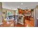 Open kitchen with wooden cabinets, bar seating, stainless steel appliances, and a dining area with bright, natural light at 705 Ridge Gate Dr, Brownsburg, IN 46112